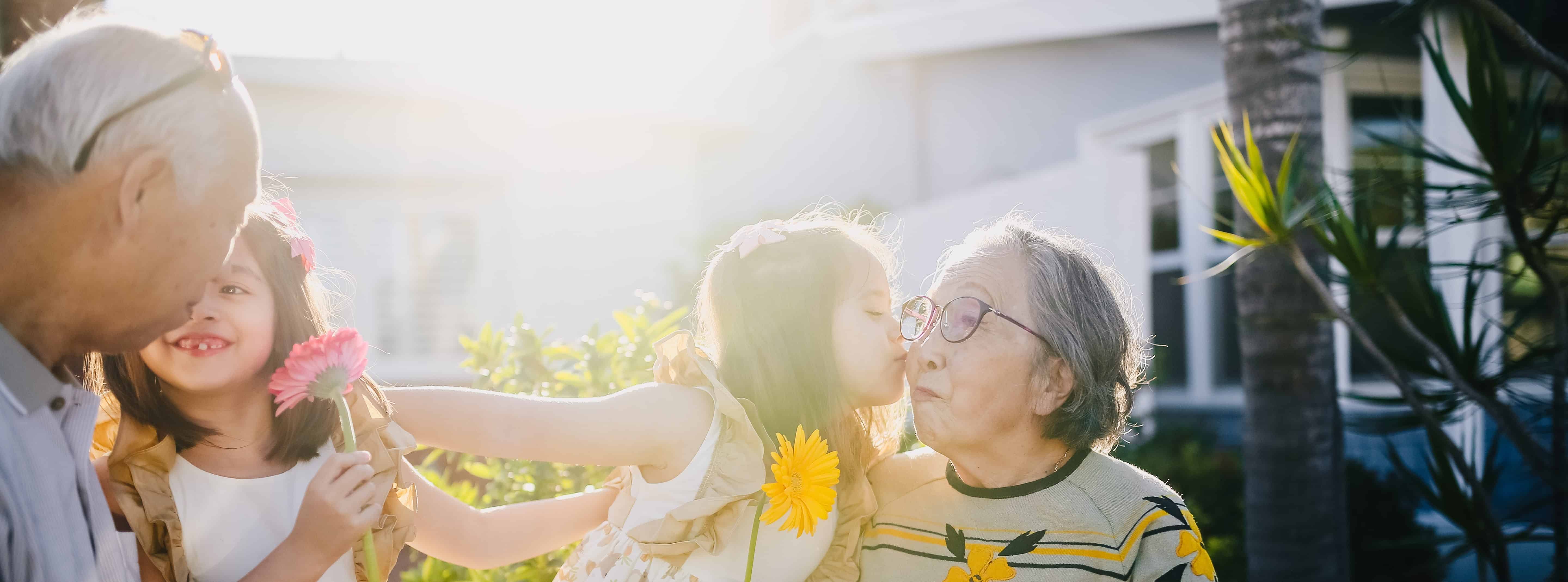 Caring grandparents with grandchildren holding flowers in sunshine